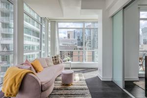 a living room with a couch and large windows at CN Tower Views - 2BR Condo - Balcony - Fast Wi-Fi in Toronto +24 photos