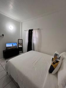 a bedroom with a white bed and a flat screen tv at Cozy Endz in Castries