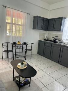 a kitchen with black cabinets and tables in a room at Cozy Endz in Castries