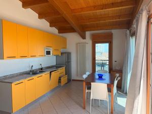 a kitchen with yellow cabinets and a table with chairs at Monaco Apartments in Lignano Sabbiadoro