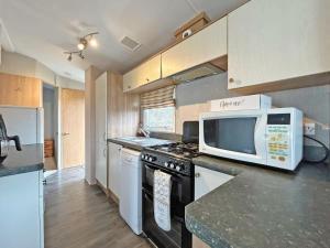 a kitchen with a microwave and a stove at Brechin Getaway the rowan 2 bedroom static in Angus +3 photos
