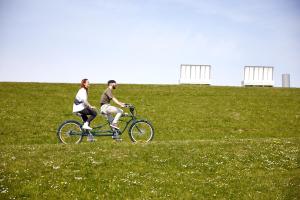 a man and woman riding a bike in a field at Bretterbude Büsum in Büsum +93 photos