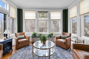 a living room with chairs and a table and windows at Historic Salyards Mansion by Heirloom Boutique Collection in Duluth