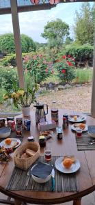 a wooden table with food on it in front of a window at MAISON d'Hôtes AFRIKA du QUEYROUX , petit gite en campagne proche BERGERAC, 1 seul animal accepté sur demande in Ginestet