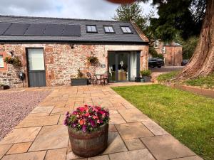 a brick house with a pot of flowers in front of it at Stable Cottage in Lockerbie