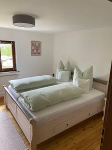 a bedroom with a large bed with white sheets and pillows at Bergliebe in Weitnau