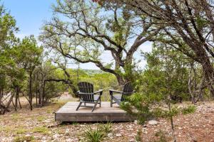 two chairs sitting on a wooden platform under a tree at Camp Jackalope - Outdoor Trails - Fire Pit - Views in Wimberley