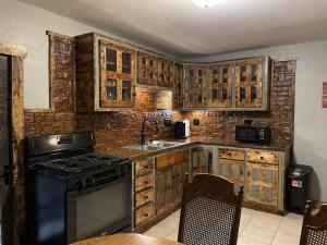 a kitchen with wooden cabinets and a sink and a stove at The Miner's Getaway in Lead SD in Lead