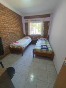a bedroom with two beds and a brick wall at El Rincón de mis Abuelos in Albardón
