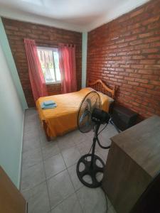 a bedroom with a bed with a fan and a brick wall at El Rincón de mis Abuelos in Albardón