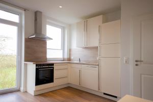a kitchen with white cabinets and a window at Ferienwohnung BEA 2 in Rabenkirchen-Faulück