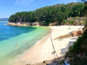 a beach with a group of people in the water at The Cliffs - Morandaina Beach in O Vicedo