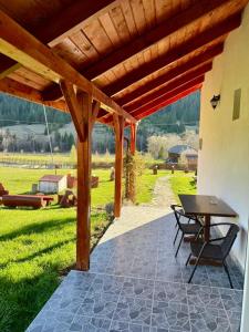 a patio with a table and chairs under a wooden roof at Casa Chindea Lacu Rosu in Lacu Rosu