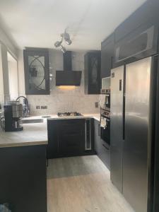 a kitchen with black cabinets and a stainless steel refrigerator at Private room with private bathroom in Hackington