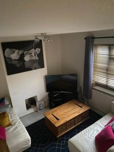 a living room with a coffee table and a flat screen tv at Private room with private bathroom in Hackington