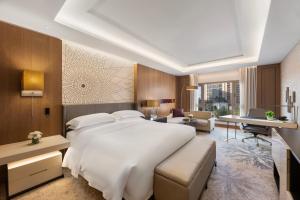 a bedroom with a large white bed and a living room at InterContinental Doha Beach & Spa by IHG in Doha
