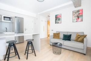 a living room with a couch and two bar stools at URBANSEA Las Palmas in Las Palmas de Gran Canaria