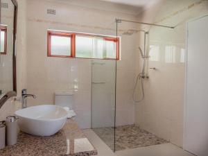a bathroom with a tub and a glass shower at Tuli House in Harare +7 photos
