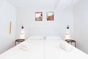 two beds in a white room with pictures on the wall at URBANSEA Las Palmas in Las Palmas de Gran Canaria