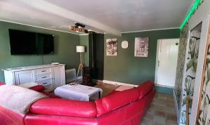 a living room with a red couch and a tv at Maison des Roses in Béalencourt