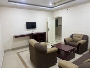 a living room with two chairs and a television at Staio Rooms in Thodupuzha +14 photos