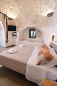 a bedroom with a large bed with a stone wall at Pavì Trulli e Suites in Locorotondo