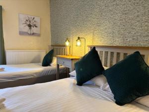 a hotel room with two beds with green pillows at The New Inn in Oswestry