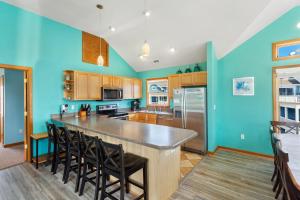a kitchen with blue walls and a large island with chairs at 1008 - Shellous in Corolla