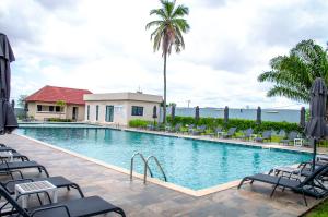 ein Schwimmbecken mit Stühlen und Palmen in der Unterkunft Seen Ran Hotel Bouake in Bouaké