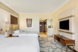 a hotel room with two beds and a flat screen tv at InterContinental Doha Beach & Spa by IHG in Doha
