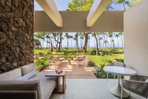 a patio with chairs and tables and palm trees at Mauna Kea Beach Hotel, Autograph Collection in Hapuna Beach