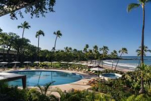 a swimming pool with umbrellas and a beach at Mauna Kea Beach Hotel, Autograph Collection in Hapuna Beach
