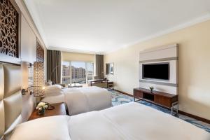 a hotel room with two beds and a flat screen tv at InterContinental Doha Beach & Spa by IHG in Doha