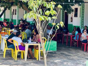 a group of people sitting at tables under a tree at Carranca Grande Hotel in Xique-Xique