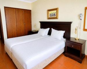 a bedroom with a large bed with white sheets at Aparthotel Navigator in Sagres