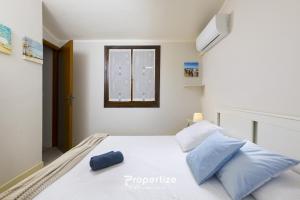 a bedroom with a white bed with blue pillows at Il terrazzo sulla duna 5 by Propertize in Marrùbiu