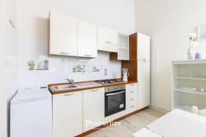 a white kitchen with white cabinets and a sink at Il terrazzo sulla duna 5 by Propertize in Marrùbiu