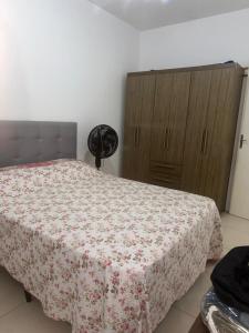 a bedroom with a bed with a flowered blanket on it at Germinada in Imbé