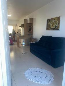 a living room with a blue couch and a kitchen at Germinada in Imbé