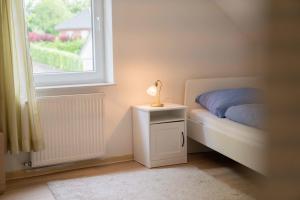 a bed with a lamp on a night stand next to a window at Ferienwohnung Kaufmann 3 in Rabenkirchen-Faulück