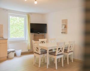 a white dining room table with chairs and a television at Ferienwohnung Kaufmann 3 in Rabenkirchen-Faulück