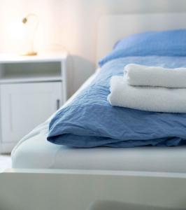 a bed with blue sheets and white towels on it at Ferienwohnung Kaufmann 3 in Rabenkirchen-Faulück +2 photos