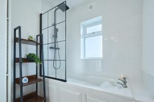 a bathroom with a tub and a shower with a window at Cosy Peak District Cottage Walk to Town Centre in Fairfield