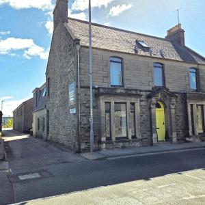 an old brick building with a yellow door on a street at Weston House Keith in Keith
