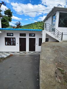 a white building with two garage doors and a hill at Shaaneshwar Mahadev Hotel & Restaurant in Phata