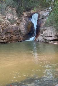 a waterfall next to a body of water at Camping Cachoeira Bem Vinda in Itabirito