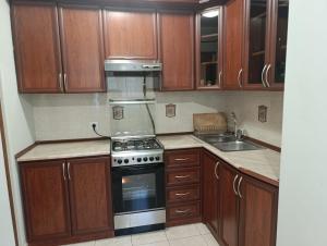 a kitchen with wooden cabinets and a stove and a sink at Benefice Apart in Yerevan