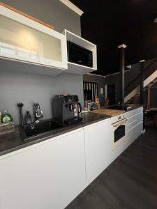a kitchen with white cabinets and a sink and a microwave at MaxiMar Apartment With Sauna in Valga