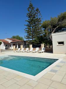 a swimming pool with chairs and a tree in the background at Villa Noesyr in Neviano