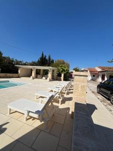 a row of white lounge chairs next to a pool at Villa Noesyr in Neviano